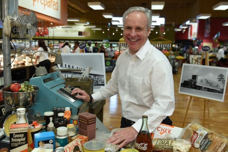 Southeastern Grocers’ new president and CEO, Anthony Hucker, poses with a 1956-themed checkout lane.