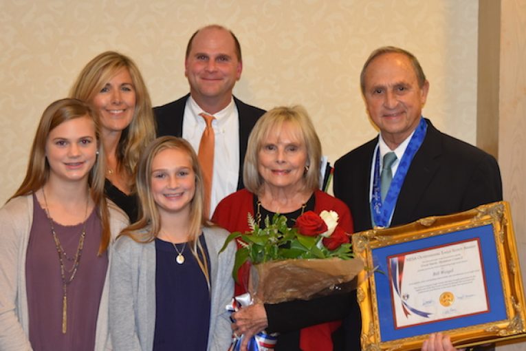 Bill Weigel, right, holds his framed Eagle Scout award. Family members include his wife, Ann, (in red) and their son, Kurt, with his family, from left, daughter Karley, wife Carolyn and daughter Abby.