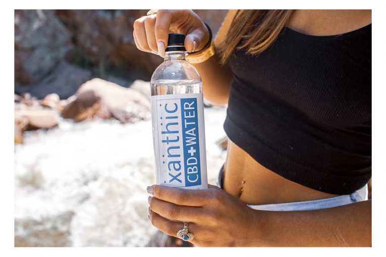 A woman holding a bottle of Xanthic CBD Water