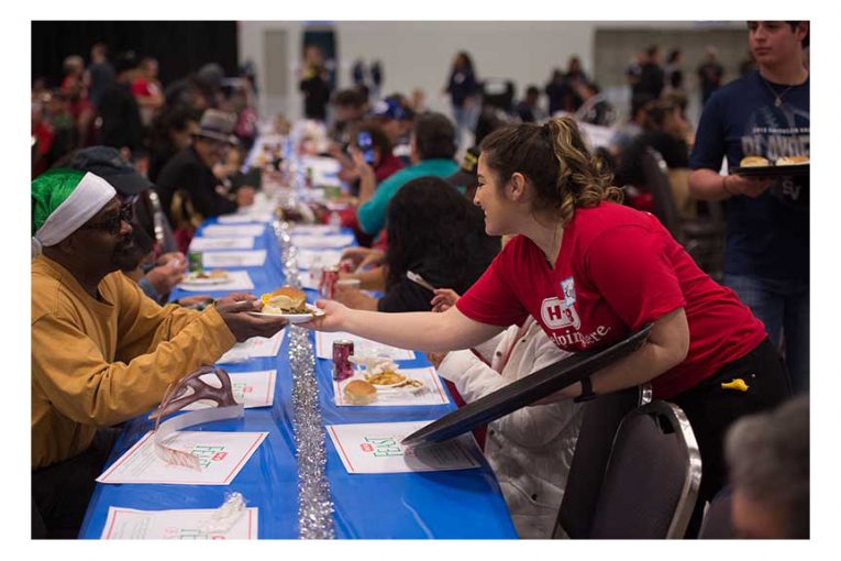 A volunteer hands a man a plate of food at a Feast of Sharing event.